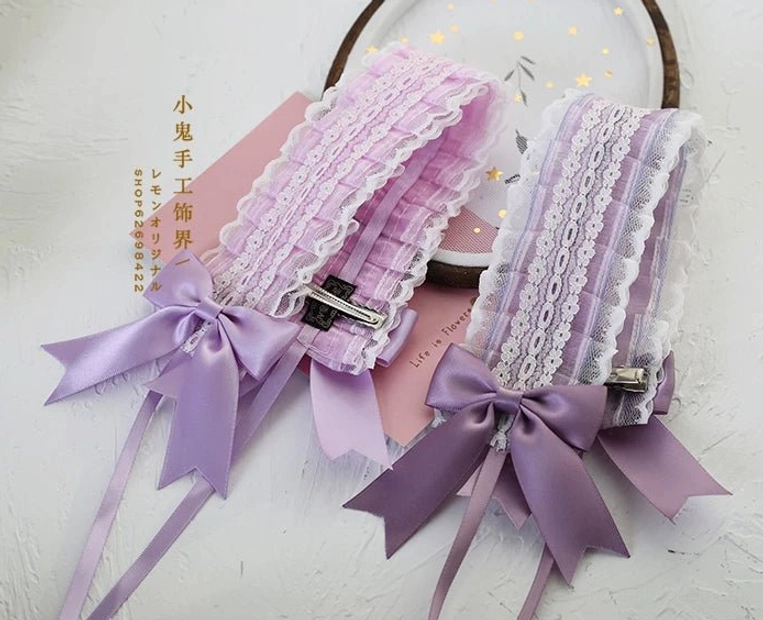 Close-up flat lay of light purple ruffled lace lolita headband with purple satin bow secured by metal hair clip on pink background
