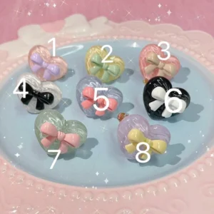 Sweet Lolita heart bow adjustable ring collection with eight numbered pastel, translucent, and black white styles displayed on a blue dessert tray