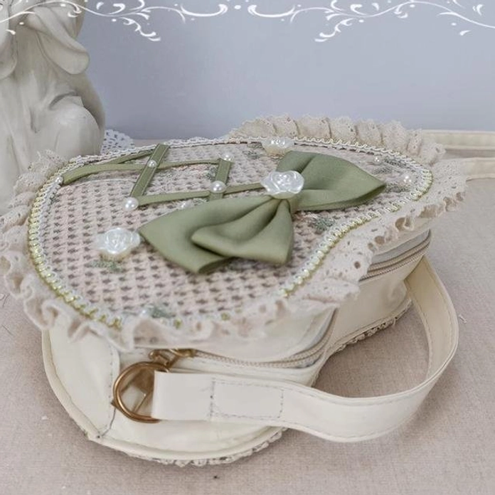 Close-up of Sweet Lolita heart crossbody bag gold strap buckle zippered opening ruffled lace edge and green bow detail