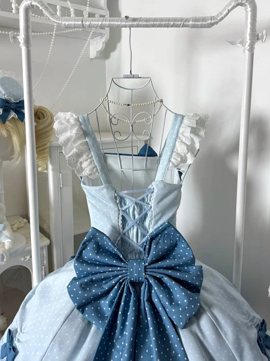 Sweet Lolita JSK dress front close-up hanging view showing lace-up corset style bodice, oversized polka dot blue waist bow, ruffled flying sleeves, and detailed construction