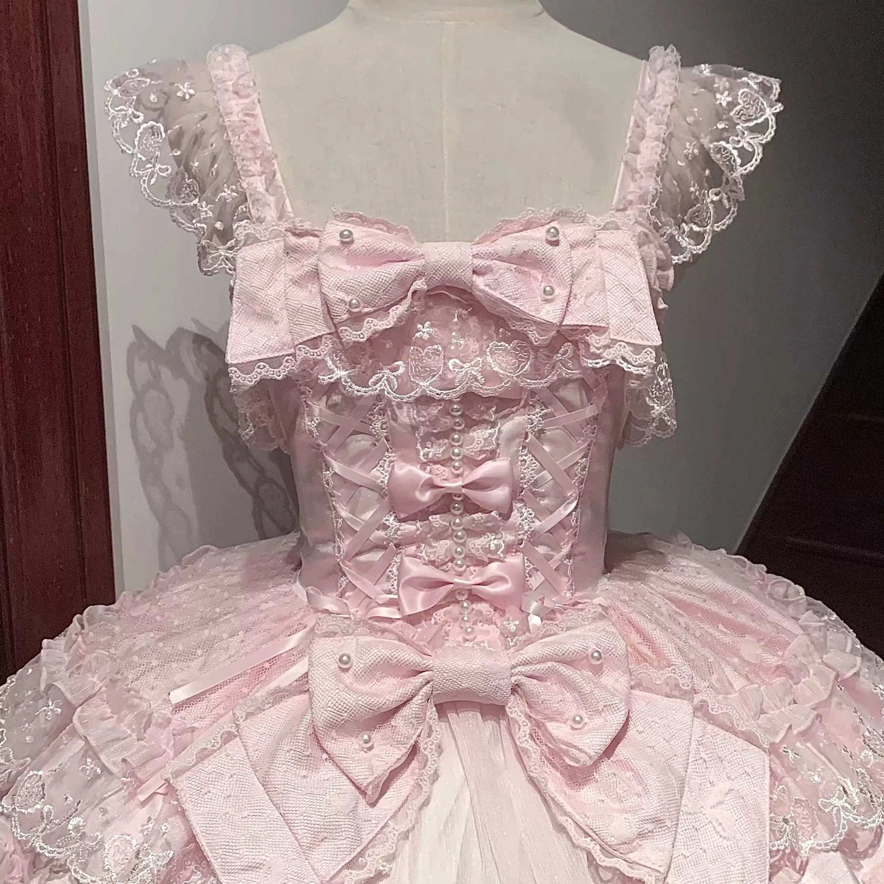 Sweet Lolita jumper skirt close-up detail of bow embellishments, decorative stitching, and lace appliqué work on bodice