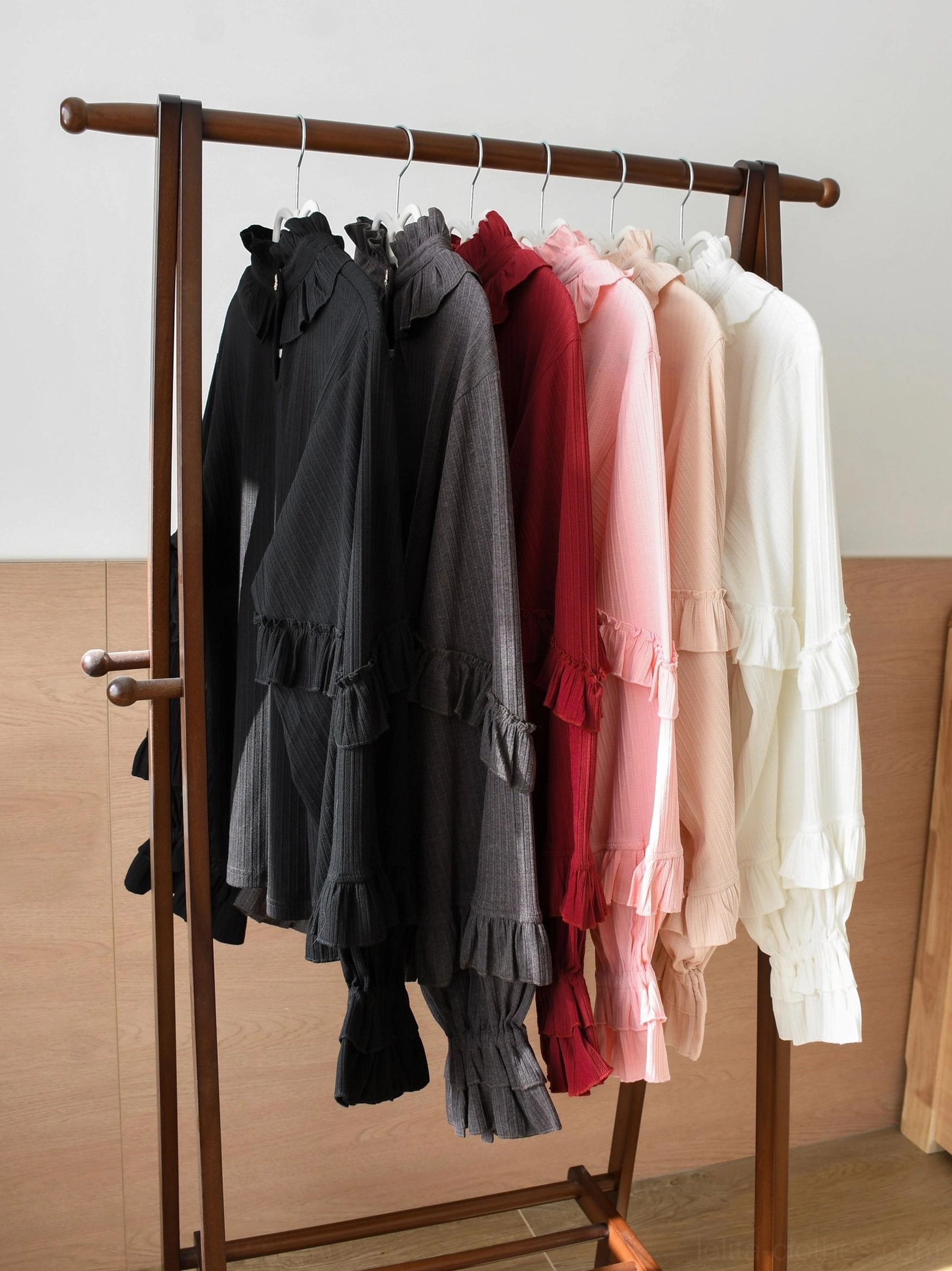Multiple color options of sweet lolita knit inner blouses displayed on wooden rack including black burgundy and off-white variations with ruffled sleeves