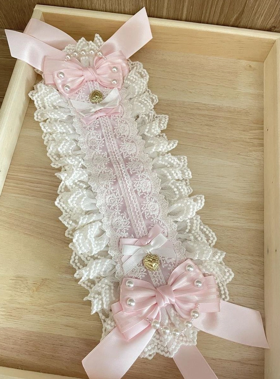 Full flat lay of Sweet Lolita lace bonnet hairband, double ruffled white lace edges, pink and white satin bows with pearl and gold heart accents, long adjustable ribbon straps, wooden tray