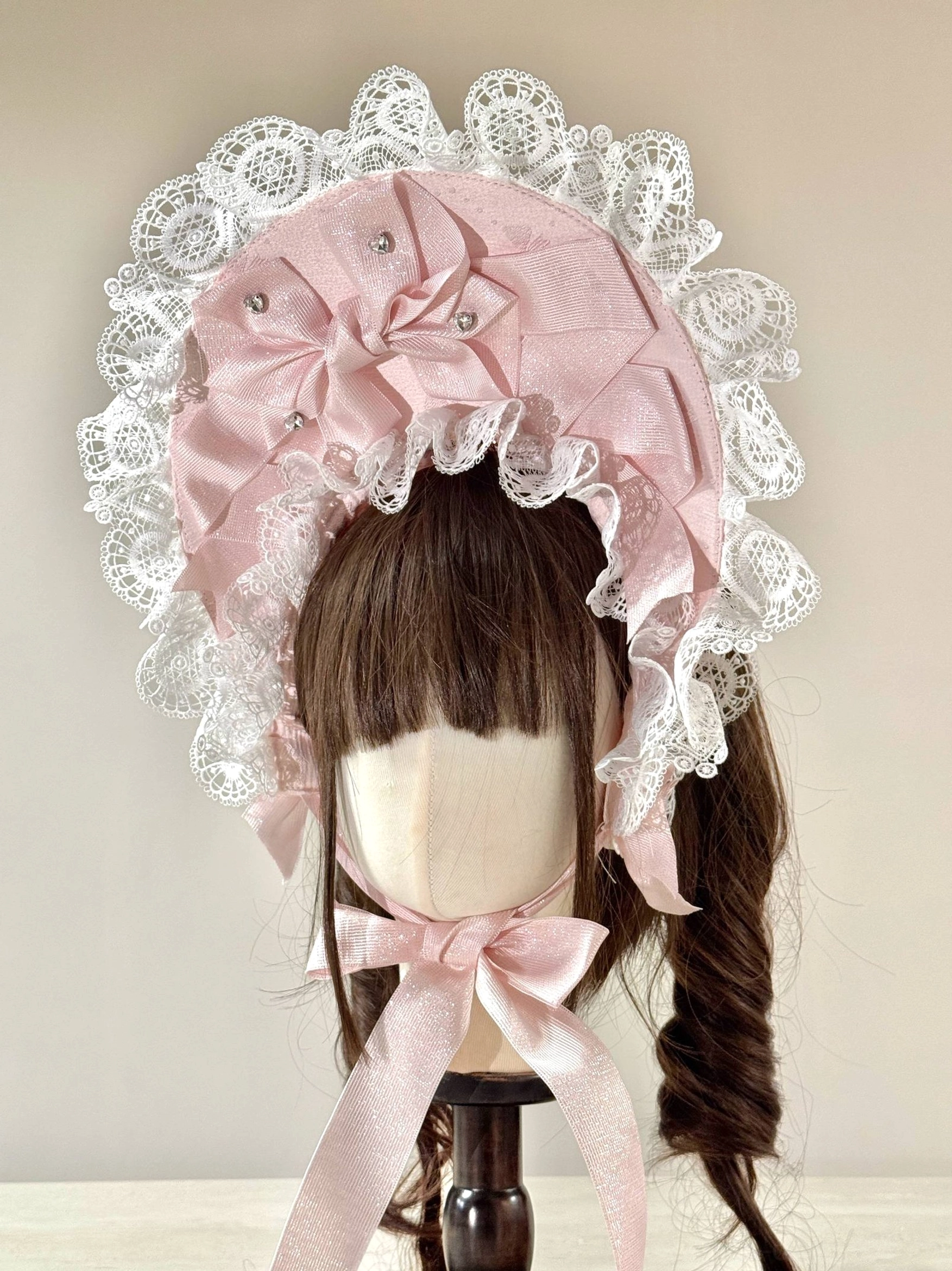 Sweet Lolita lace head bonnet featuring deep pink satin fabric, large ruffled white lace trim, prominent satin bow with pearl embellishments, matching light pink long neck ribbons