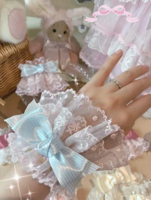 Lolita lace bow wrist cuffs close-up worn on hand with light blue satin bow and sheer floral lace showing elastic fit comfort