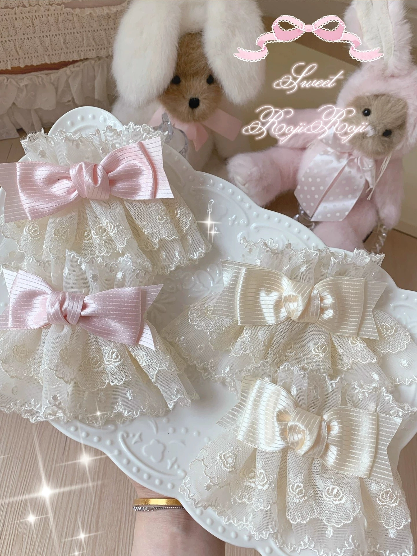 Lolita style lace bow wrist cuffs flat lay overhead view showing beige and pink two-tone options with double bow decorations on white ceramic tray
