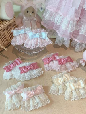 Sweet lolita lace bow wrist cuffs overhead display showing multiple color variations including pink, blue and beige options with floral lace trim and striped satin bows on wooden table