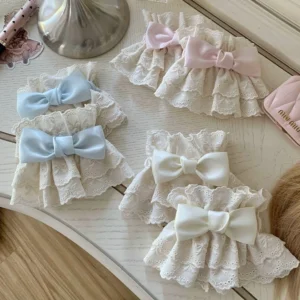Sweet Lolita lace wrist cuffs collection in three pastel color options - cream, baby blue, and pink - featuring double-layered ruffled eyelet lace with satin bow embellishments displayed on vintage wooden dressing table