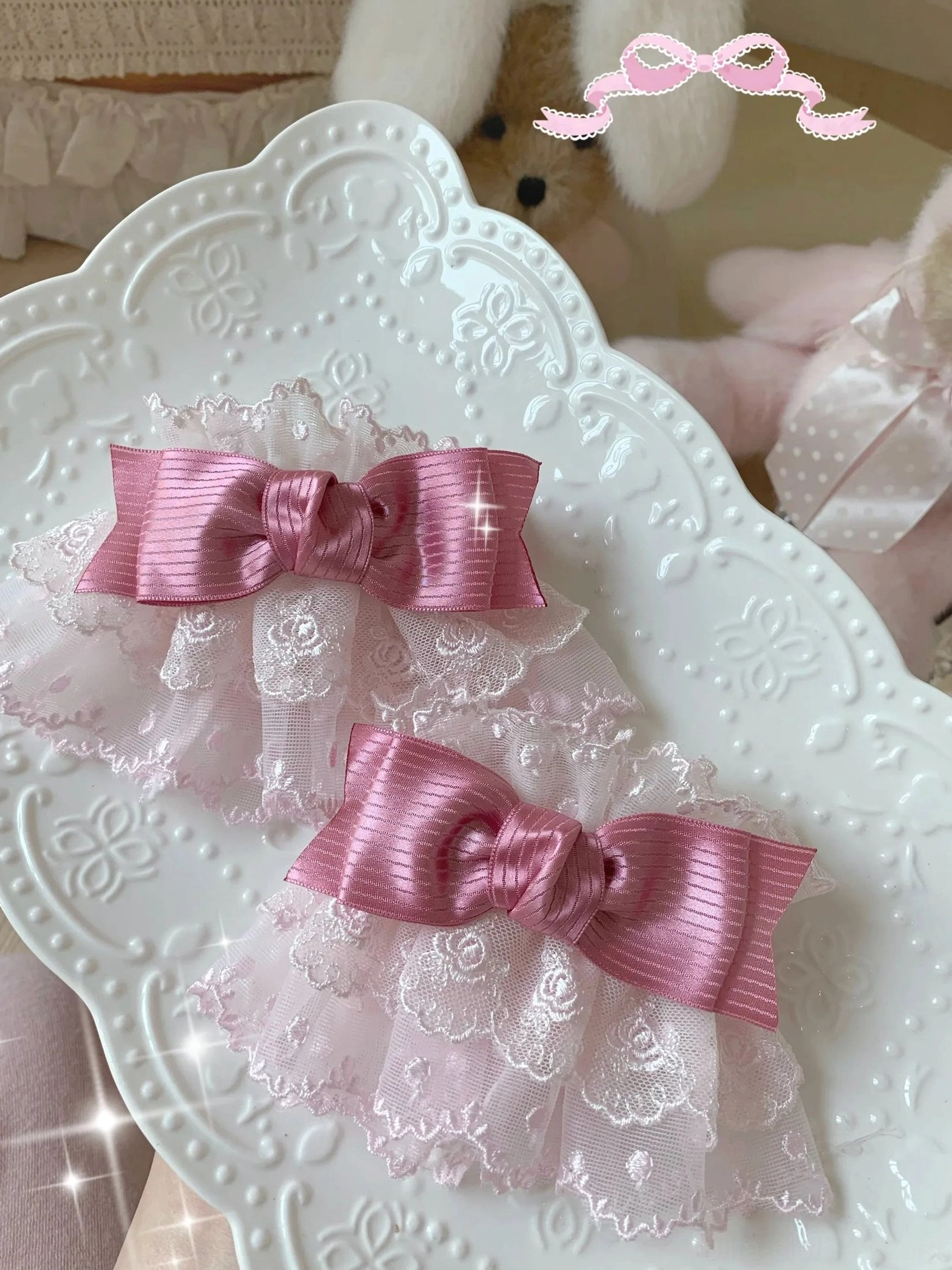 Sweet lolita lace bow cuffs flat lay view with pink lace base matched with rose red satin bows displayed on ceramic tray with plush props