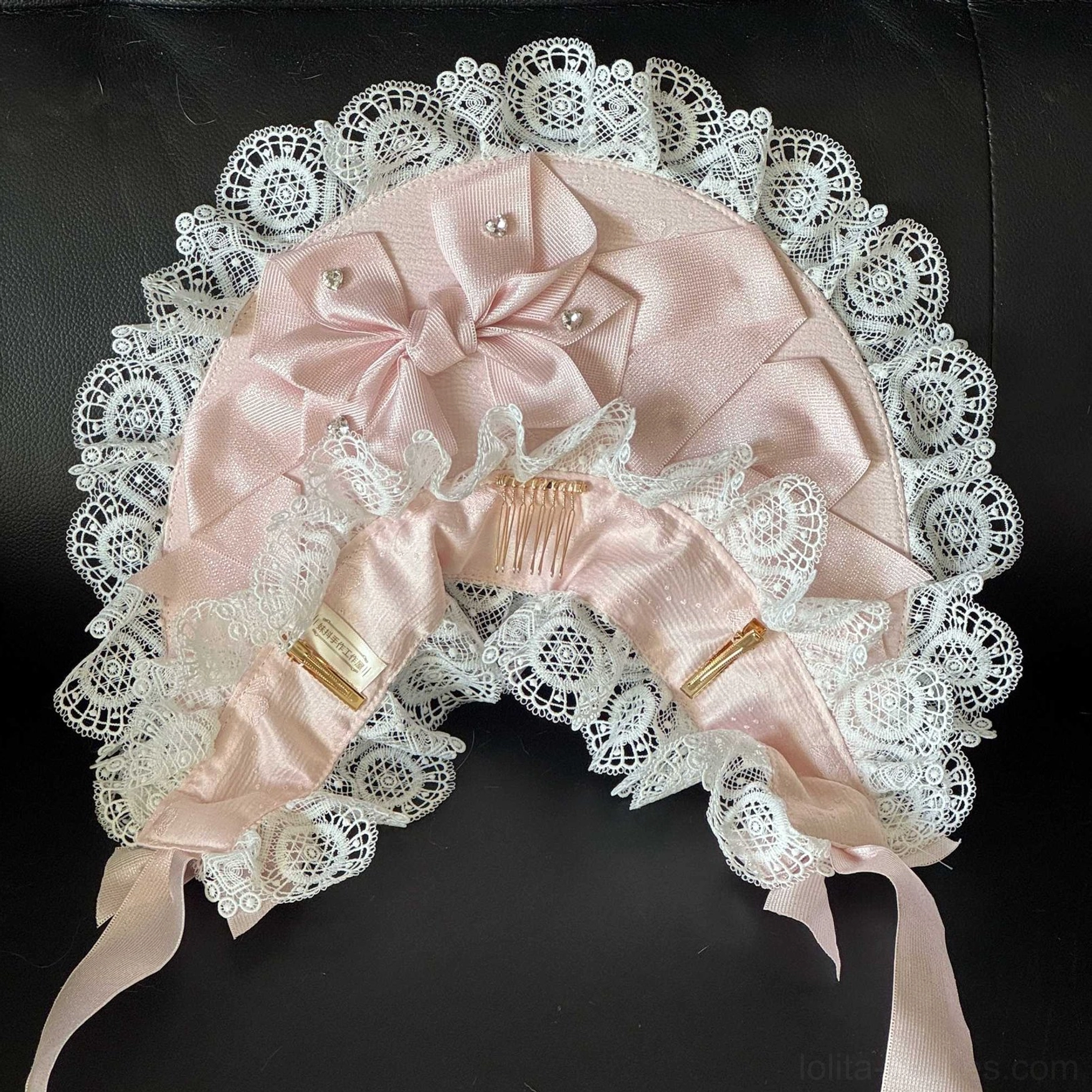 Top-down flat lay view of Sweet Lolita lace head bonnet showing light pink satin body, white ruffled lace border, built-in hair combs, long neck ribbons, pearl decorations