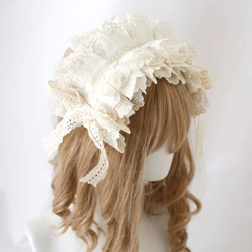 Sweet lolita embroidered lace headdress with tassel bow on blonde wig mannequin, left three-quarter view showing cream white multi-layered ruffled design with side bow details and hanging tassels