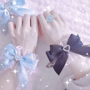 Sweet Lolita lace heart bow wrist cuffs flat lay display featuring light blue and dark purple satin bows with delicate white lace trim and sparkling heart-shaped rhinestone embellishments on plush fuzzy background