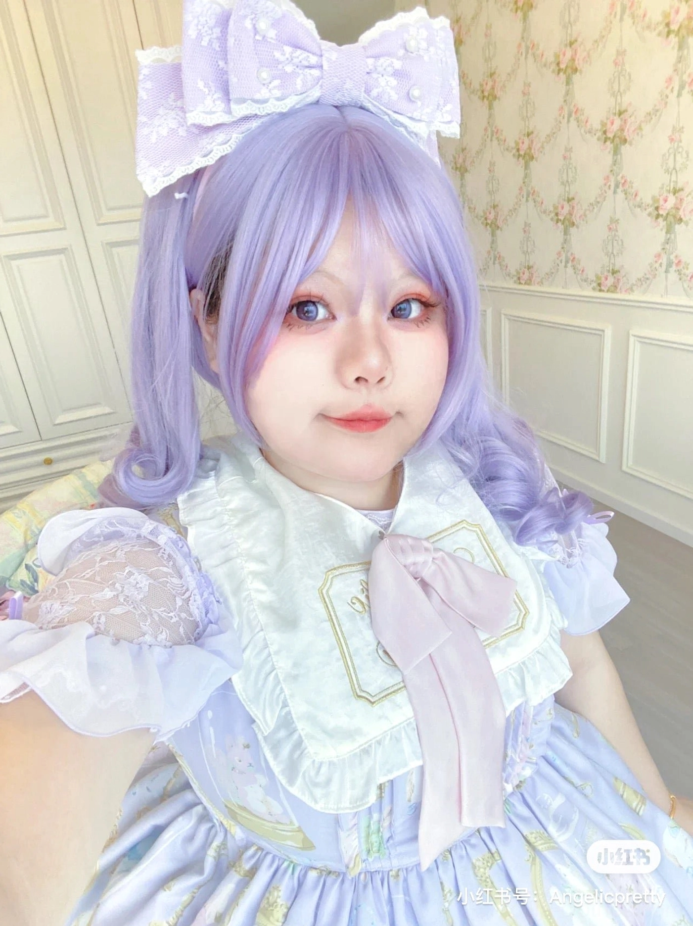 Light purple sweet lolita pearl bow KC headband worn on real model with purple twin tails and blue lolita dress vintage wall background