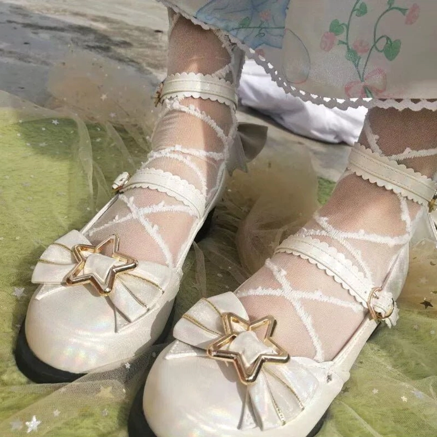 Top-down close-up of cream white sweet lolita shoes with star gold ornament front bow double ruffled ankle straps worn with lace socks and floral lolita skirt
