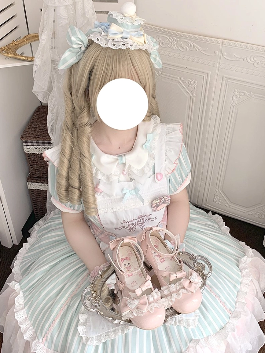 Sweet lolita mary jane heels placed on silver decorative tray held by model in vintage wall room wearing matching sweet lolita dress with cute cat print visible on insole