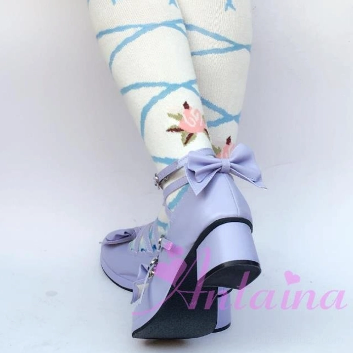 Detailed close-up of sweet Lolita Mary Jane platform shoe showing intricate crisscross strap work, metal heart-shaped buckle hardware, and bow toe ornaments