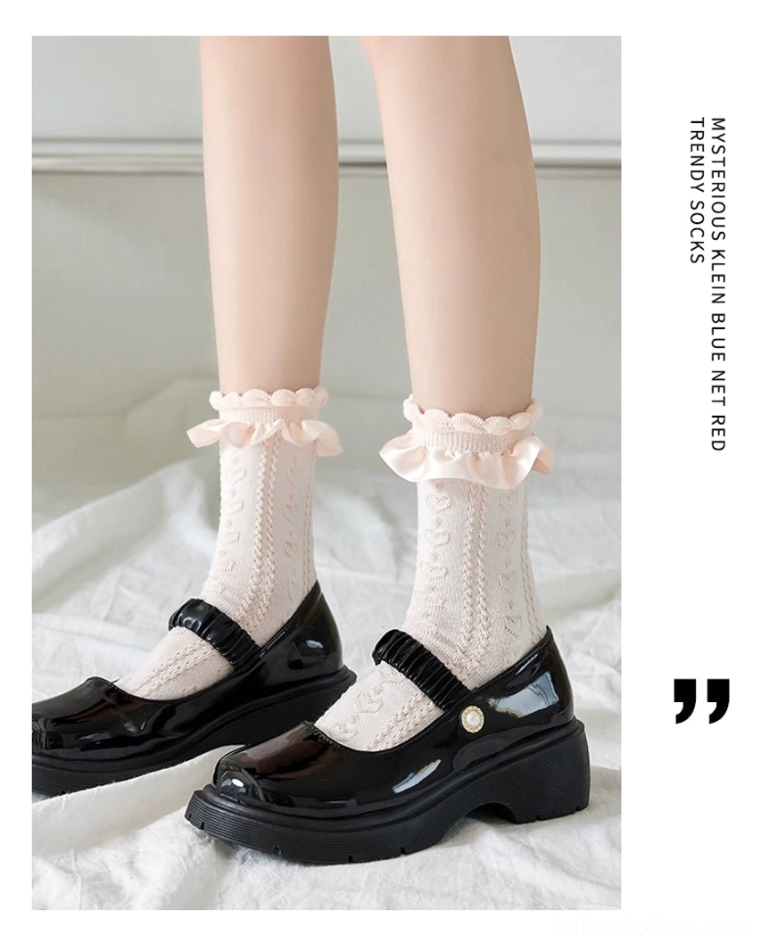 Sweet Lolita mid-calf socks with twisted hollow knit and ruffled lace ankle cuff, cream white color worn with black platform Mary Jane shoes on white bedding