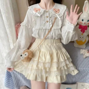 sweet lolita blouse with bear embroidery and cream tiered ruffled short skirt front half-body view with plush rabbit decorations
