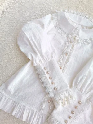 White vintage Lolita cotton blouse peter pan collar with ruffled edges and pearl buttons angled flat lay
