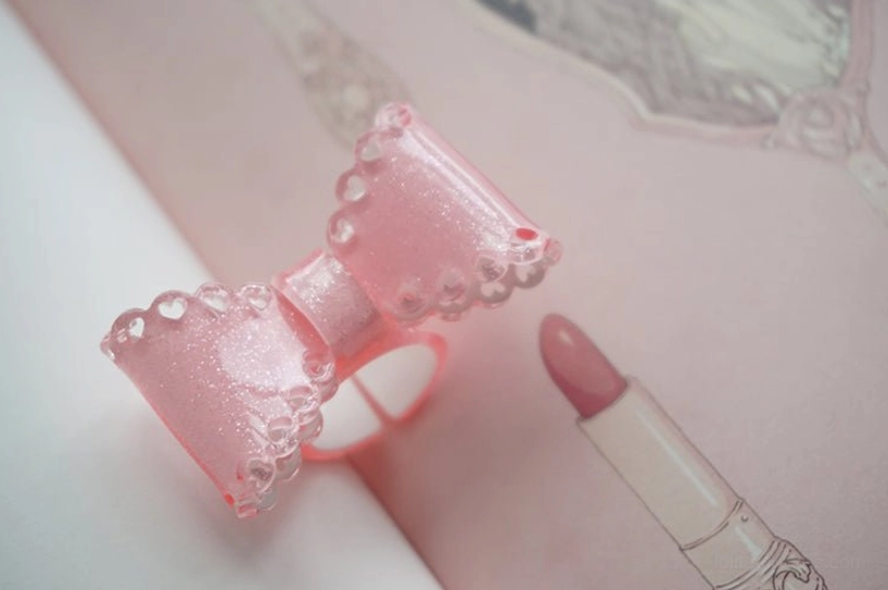 pink glitter bow ring close-up side view scalloped lace edge adjustable band open design