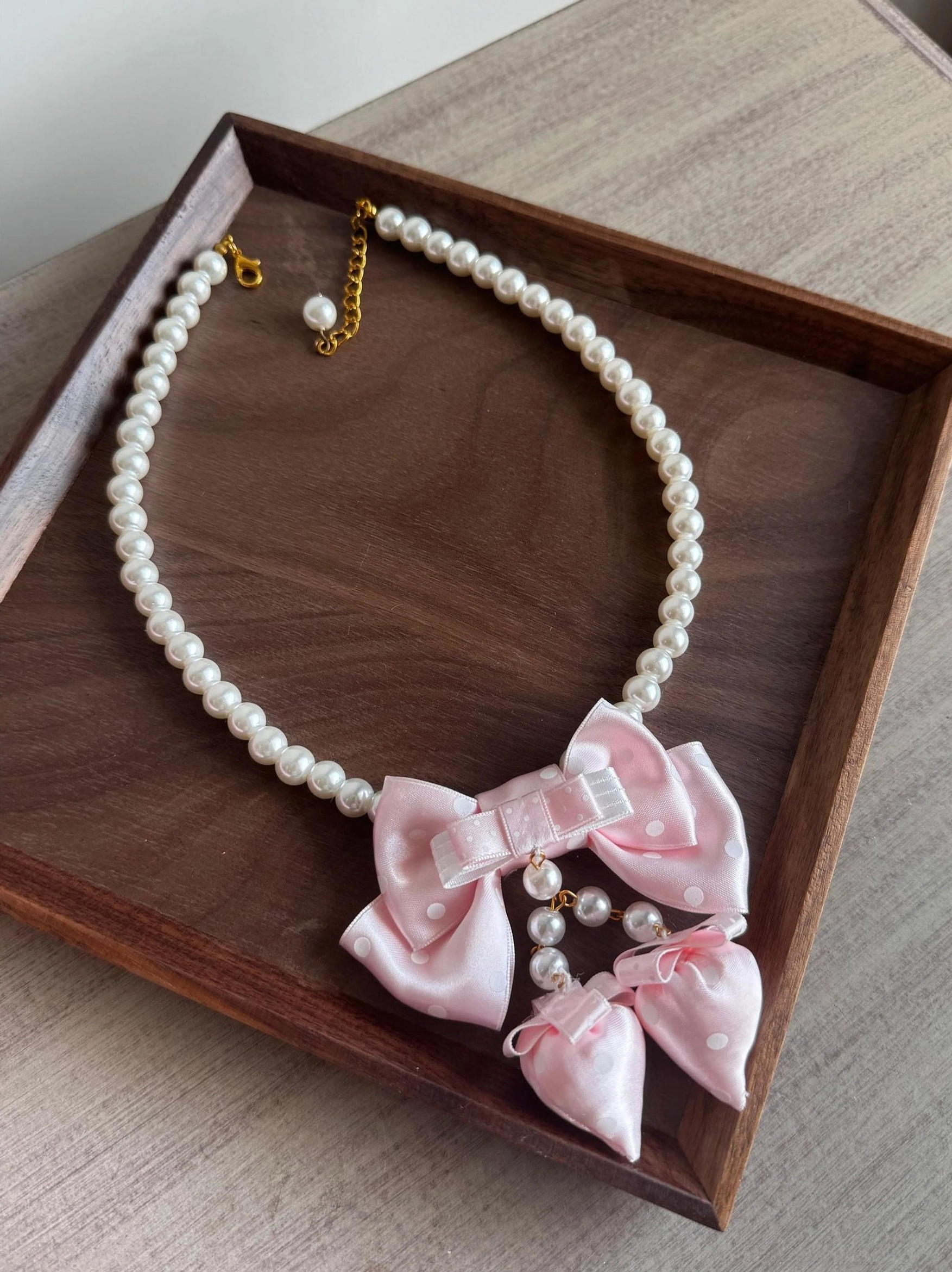 Sweet lolita pink pearl bow choker necklace overhead flat lay wooden tray imitation pearl chain satin bows details