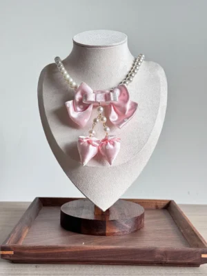 Sweet lolita pink pearl bow choker necklace with strawberry charm pendant on jewelry bust display stand wooden background