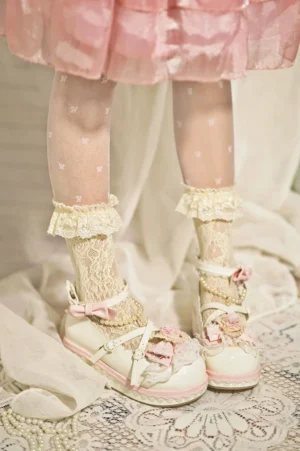Sweet Lolita platform Mary Jane shoes with light pink upper, lace trim, fabric bow and flower decorations, pearl ankle strap, worn with pink ruffled skirt and polka-dot lace socks