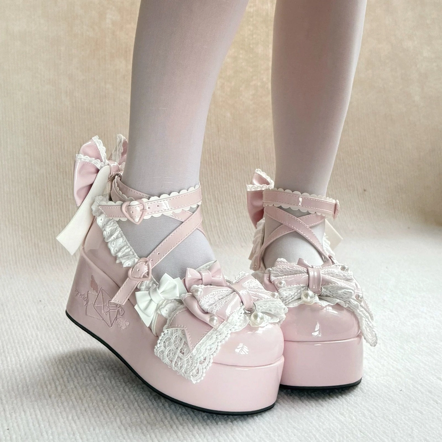 Sweet Lolita platform shoes detail shot showing embroidered envelope motif on platform side, heart-shaped buckle mechanism, structural design elements, and premium patent leather construction
