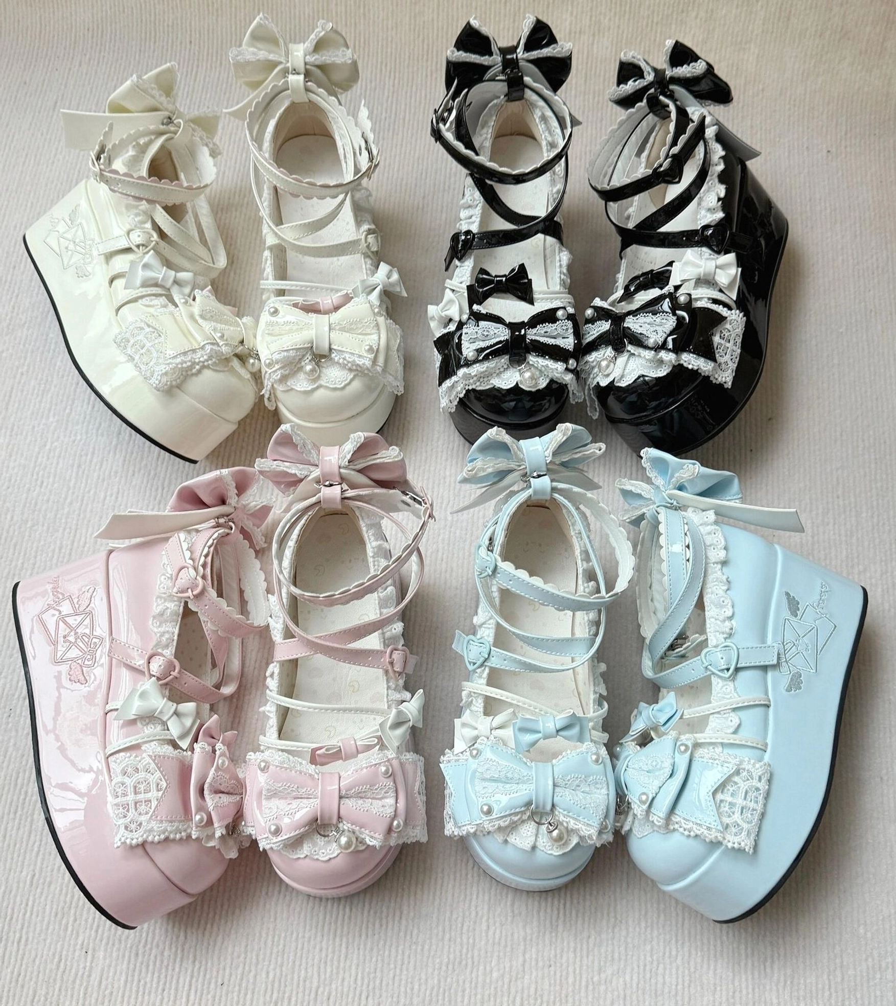 Four-color Sweet Lolita high platform shoes flat lay top-down arrangement on neutral fabric background showcasing each pair with bow and lace trims, waterproof platform sole, and glossy finish