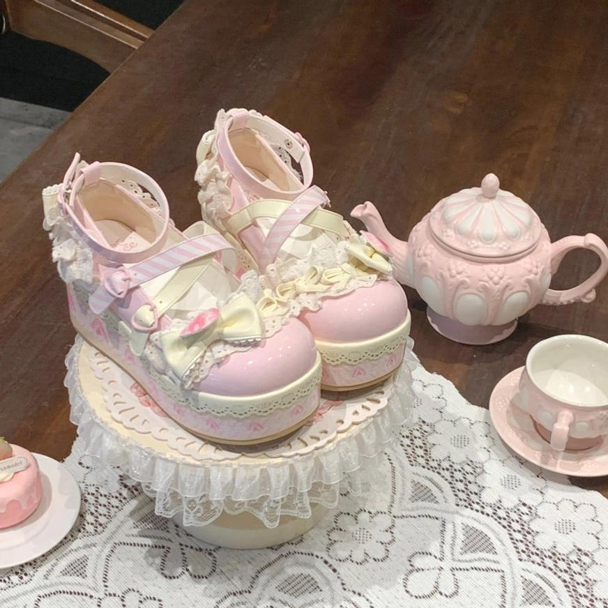 Sweet lolita platform shoes three-quarter front overhead view glossy pink upper with frilly lace decorations dual cross ankle buckle straps and heart floral ornament
