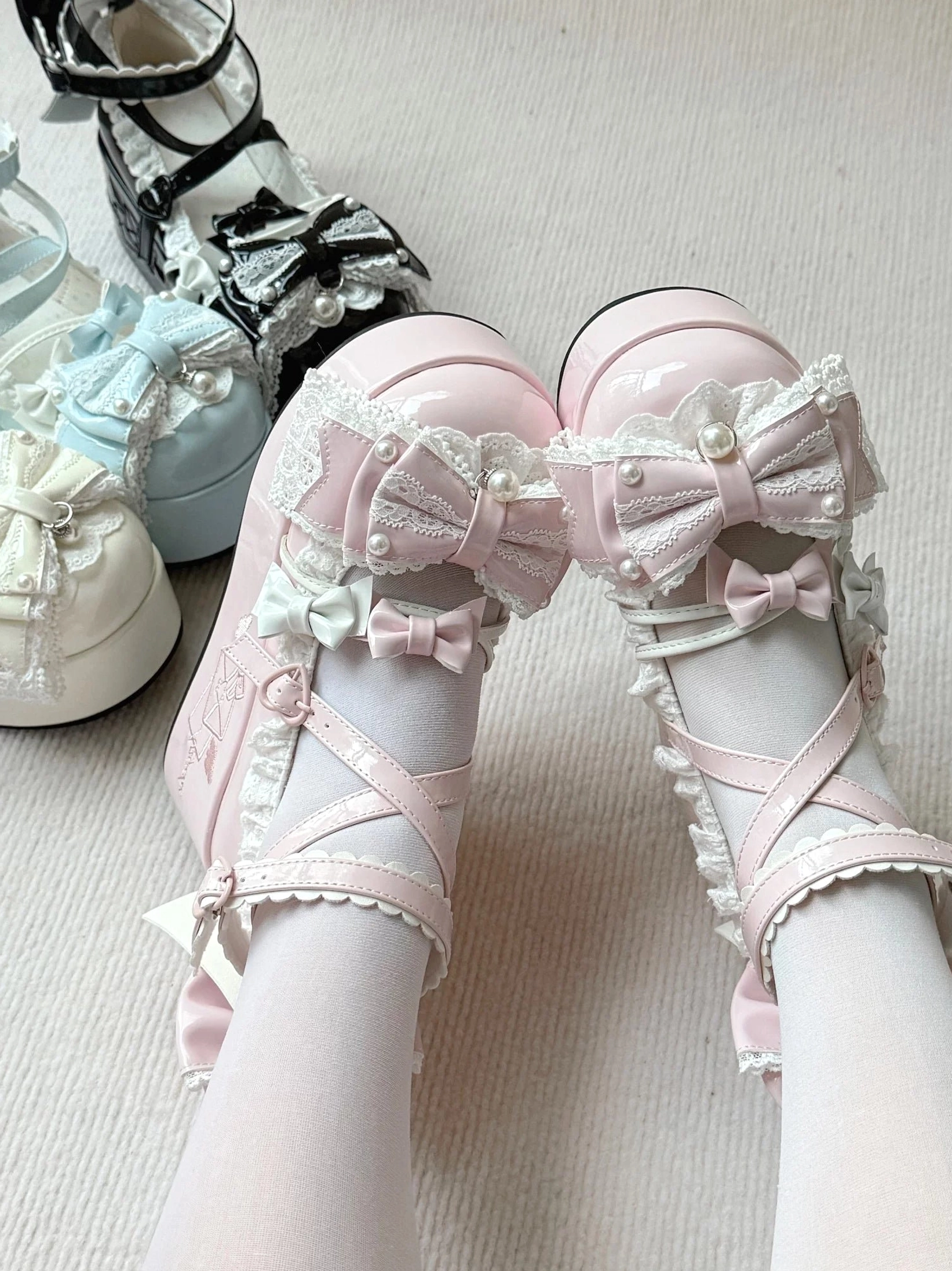 Light pink Sweet Lolita platform shoes back overhead on-foot view with double bowknots, crisscross ankle straps, glossy patent leather upper, white sheer stockings, additional color options visible