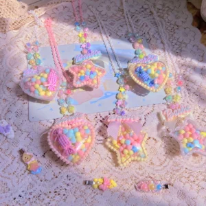 Overhead flat lay of handmade sweet lolita necklaces with pastel pom-pom heart and star pendants on vintage lace tablecloth with cute bear greeting card