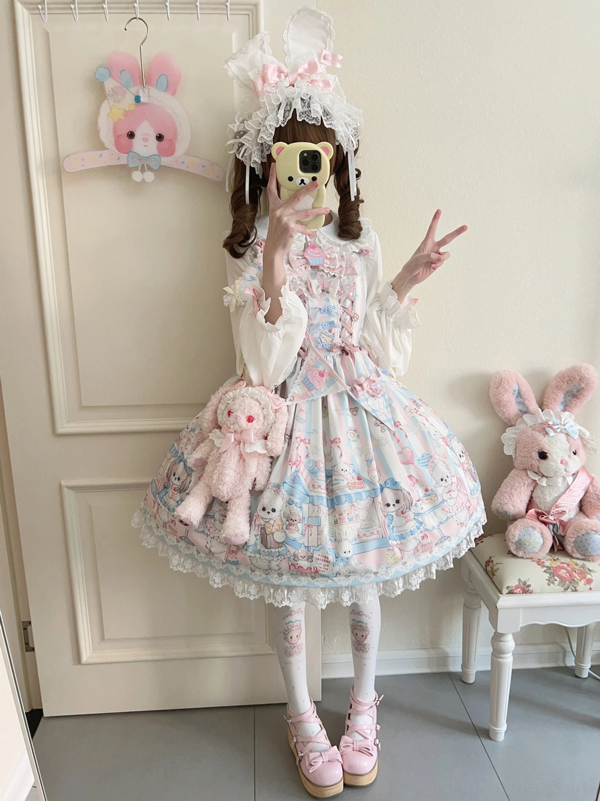 Front facing sweet Lolita girl wearing puppy print JSK jumper skirt with matching sash, peace hand gesture, holding pink plush toy bag, complete kawaii Lolita coordinate in home interior