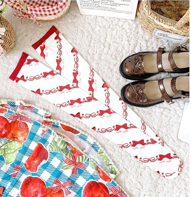 Sweet Lolita red bow and ribbon print velvet knee-high stockings unfolded flat lay showing red elasticated trim and strawberry check Lolita skirt