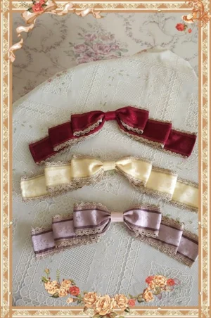 Red Sweet Lolita bow brooch with layered ribbon and delicate gold lace trim displayed on vintage lace fabric