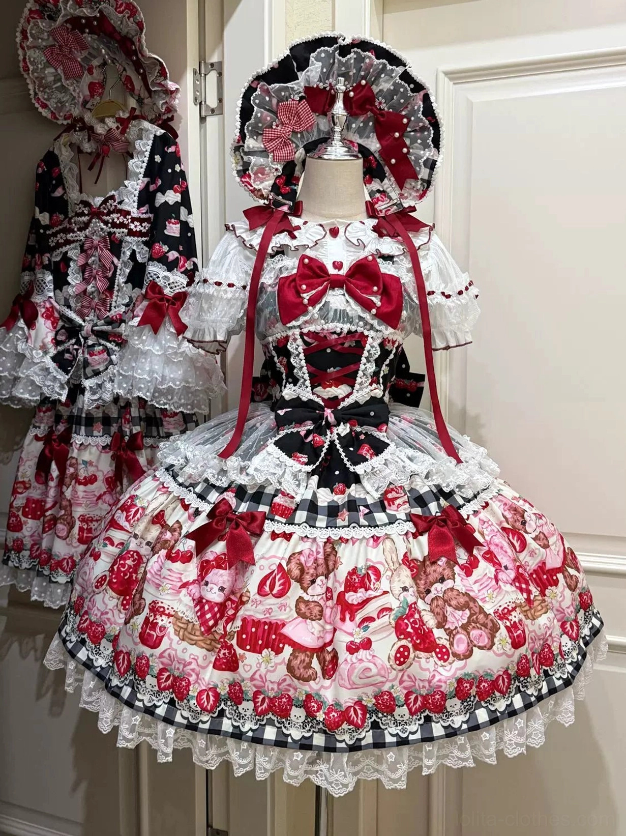 Sweet lolita strawberry bear print tiered lace JSK dress front view with red bow and layered ruffles on dress form