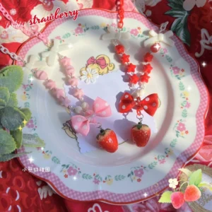 Sweet Lolita strawberry necklace with pearl beads polka dot bow displayed on pink floral porcelain plate with red background