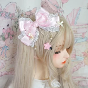 Sweet Lolita tiered bow hair clip with pearl accents worn on blonde doll, side profile showing pink satin bow with white lace edging and gold chain tassel decoration