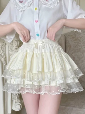 Cream white Sweet Lolita tiered ruffle bloomers with polka dot lace hem and elastic waist bow, front model view paired with doll collar shirt in vintage retro indoor living room setting demonstrating authentic Sweet Lolita coordinate