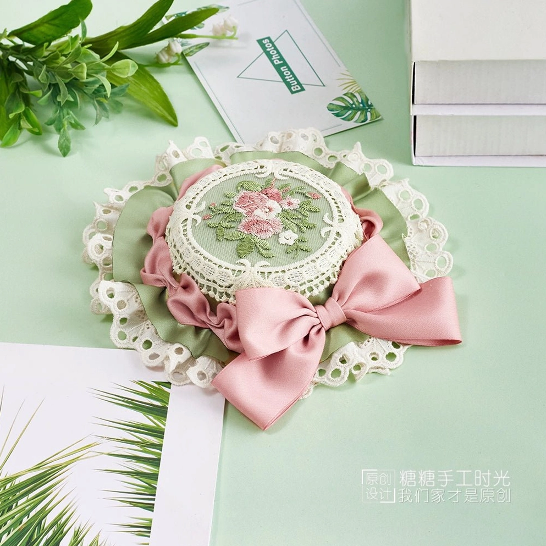 Sweet Lolita top hat accessory showing intricate hand-embroidered floral medallion, ribbon bow detail, and refined white lace trim construction quality