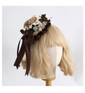 Sweet lolita top hat with mint chocolate candy details, brown satin bow, and ruffled lace base on blonde curly wig mannequin head, front three-quarter view