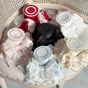 Multiple color variants of sweet Lolita bowknot top hats with tulle veils and pearl decorations arranged on rattan chair display