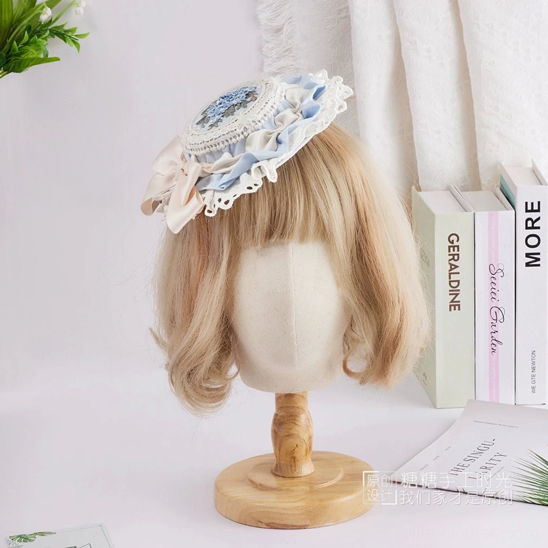 Sweet Lolita floral embroidery top hat with light blue and beige satin bow combination, intricate blue flower medallion, and elegant white lace accent