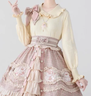 Japanese sweet Lolita two-piece matching set with beige knit top, ruffled collar, puff sleeves, and pink plaid skirt with rabbit embroidery, model wearing delicate pendant necklace making peace sign gesture, pure white background