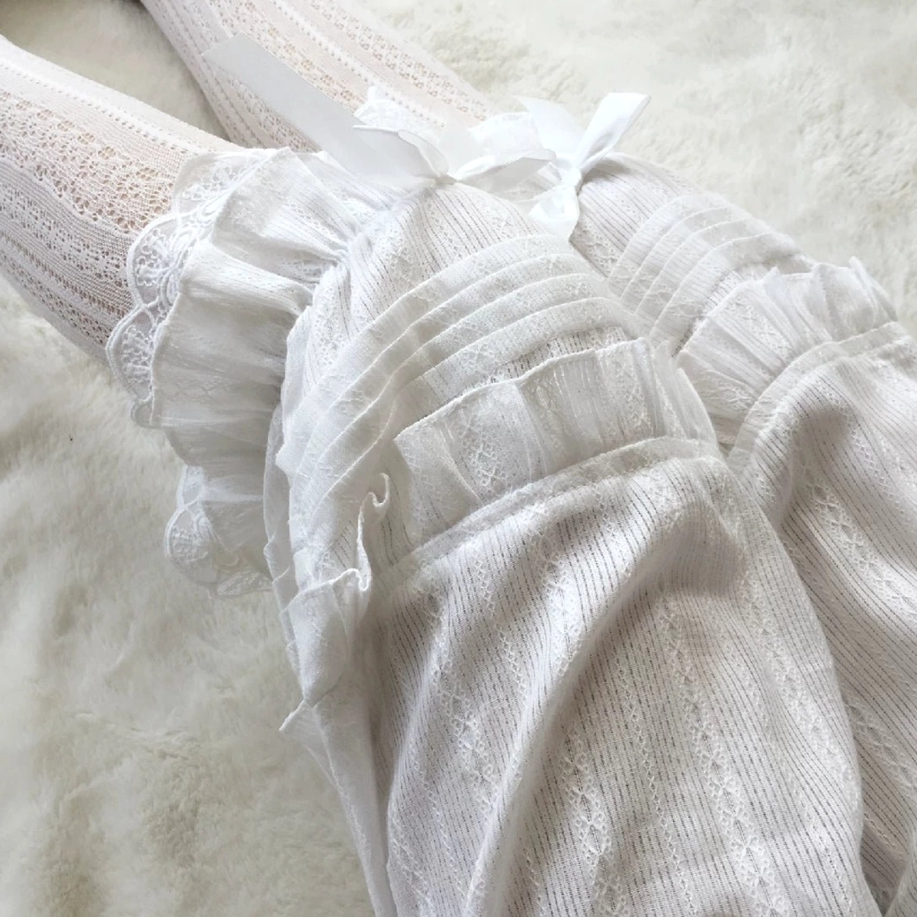 Sweet lolita white bloomers with accordion pleats and lace ruffles displayed on fluffy plush background showing full silhouette elegant layered design and construction