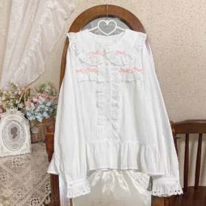 White and pink sweet lolita doll collar blouse with pink chest bows and lace-trimmed cuffs front view hanging display