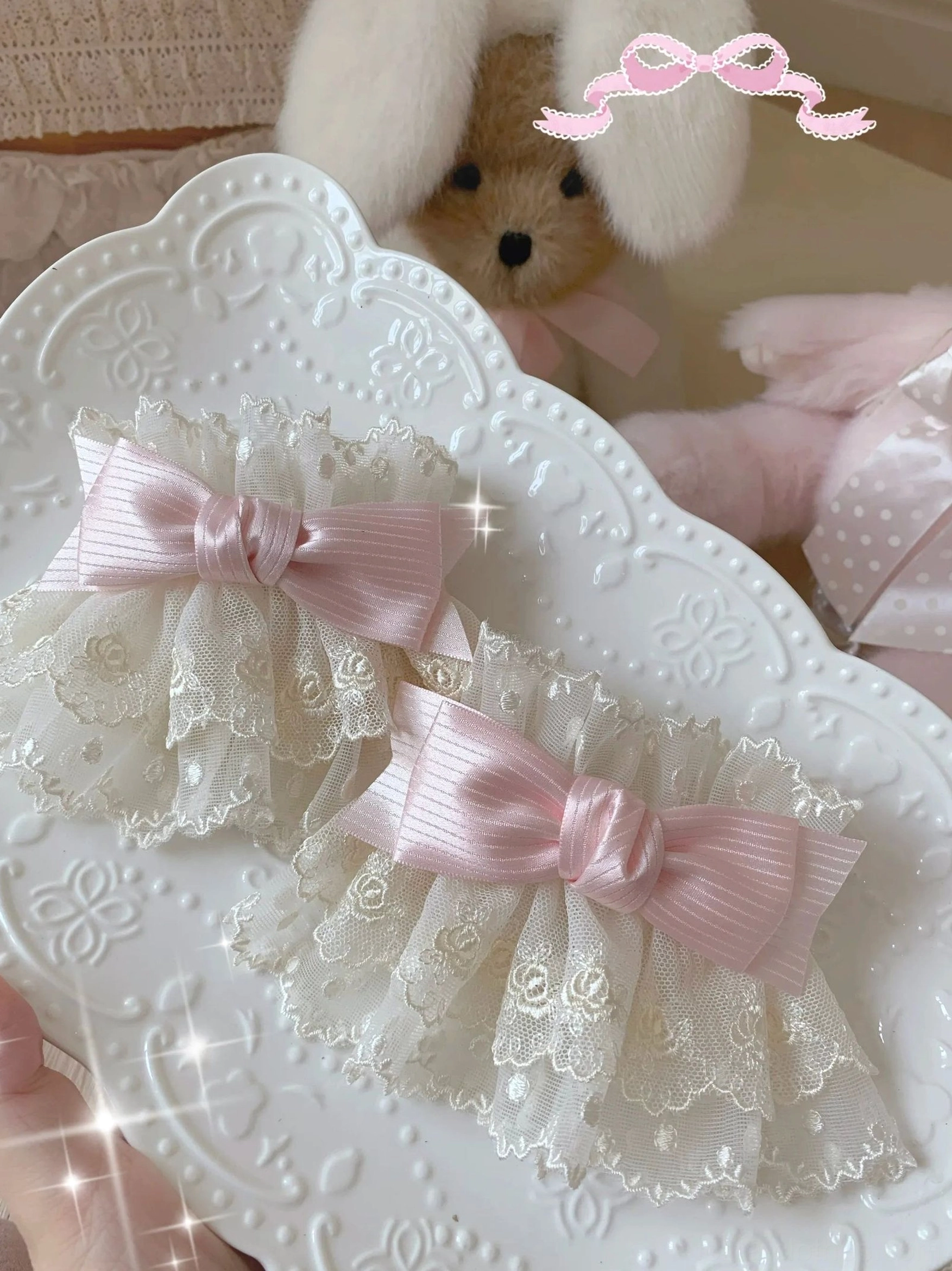 Lolita lace bow wrist cuffs overhead close-up with beige floral lace and light pink satin bows showing elegant two cuff pair
