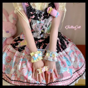 Sweet Lolita wrist cuffs with dual-color ruffled lace design featuring embroidered stars and decorative bows, styled with black JSK dress and pastel dessert print in overhead close-up view