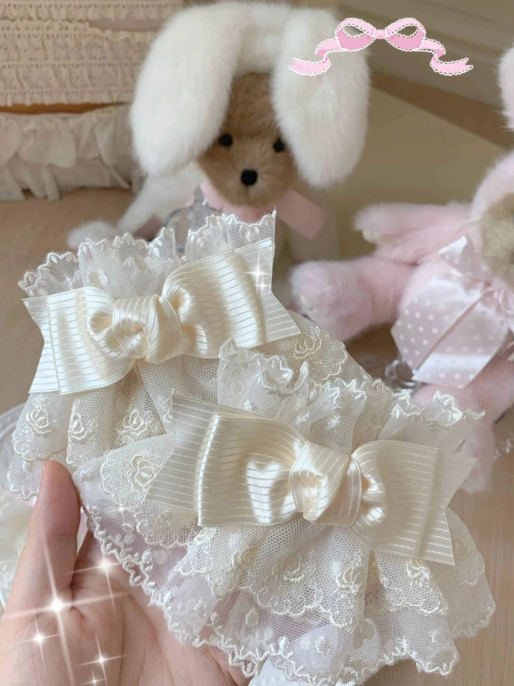 Sweet lolita lace bow wrist cuffs close-up held in hand showing pure beige color with stacked satin bows and delicate floral lace texture
