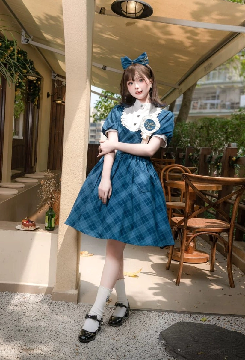 Teal blue plaid Showa retro lolita OP dress high-waisted A-line silhouette side view with matching bow worn at outdoor cafe terrace showing classic tartan fabric texture